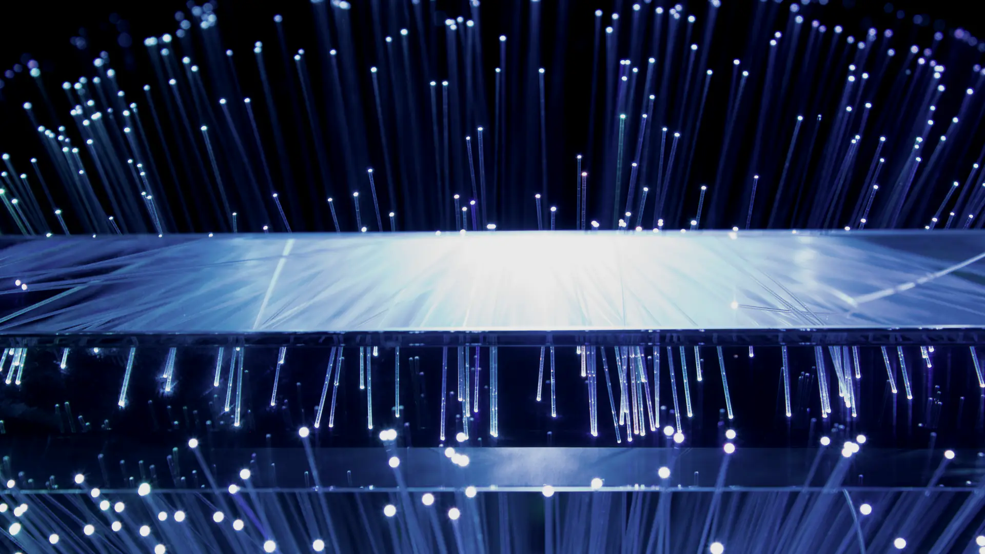 Illuminated fibre optic strands fanning out above and below a glowing glass block